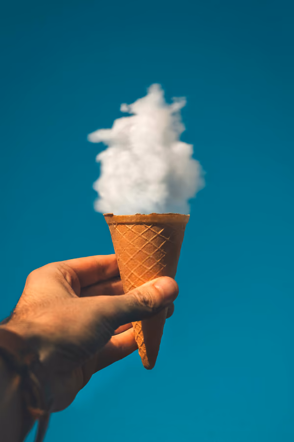 Main tenant un cornet de glace avec un nuage blanc à la place de la glace